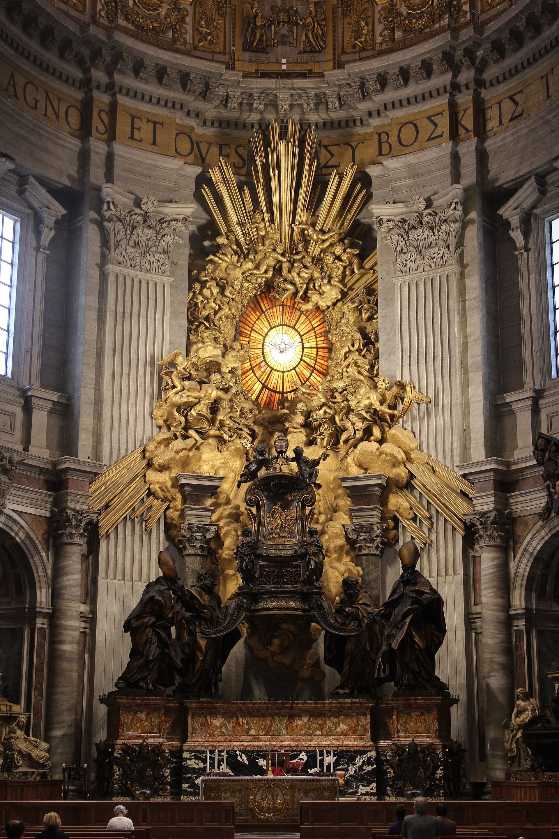 A monumental gilded bronze chair set high within a church interior, its surface catching light against the darker architecture around it.