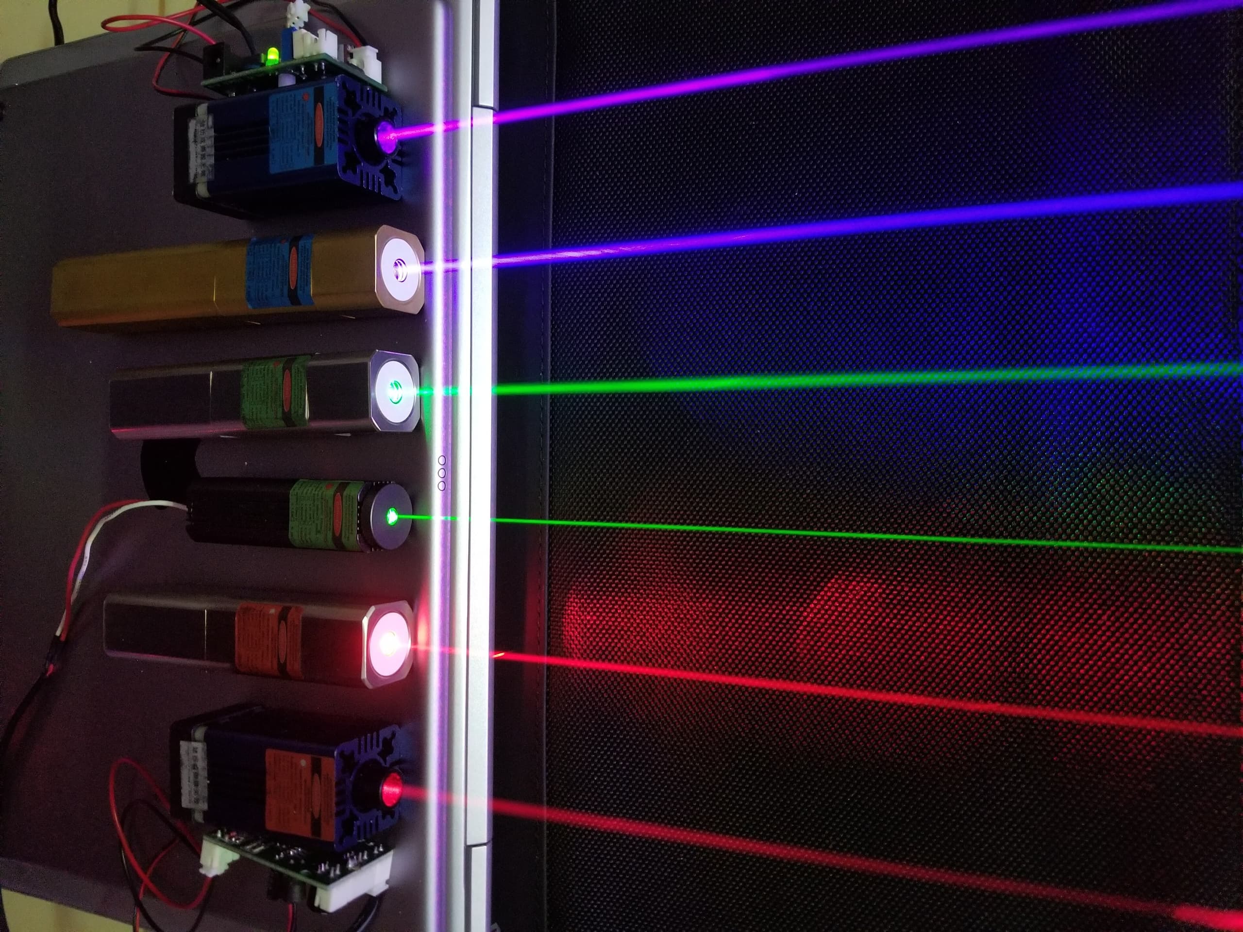 A red laser beam shown as a narrow line of light traveling through darkness, demonstrating the tight collimation that distinguishes laser light from ordinary sources.