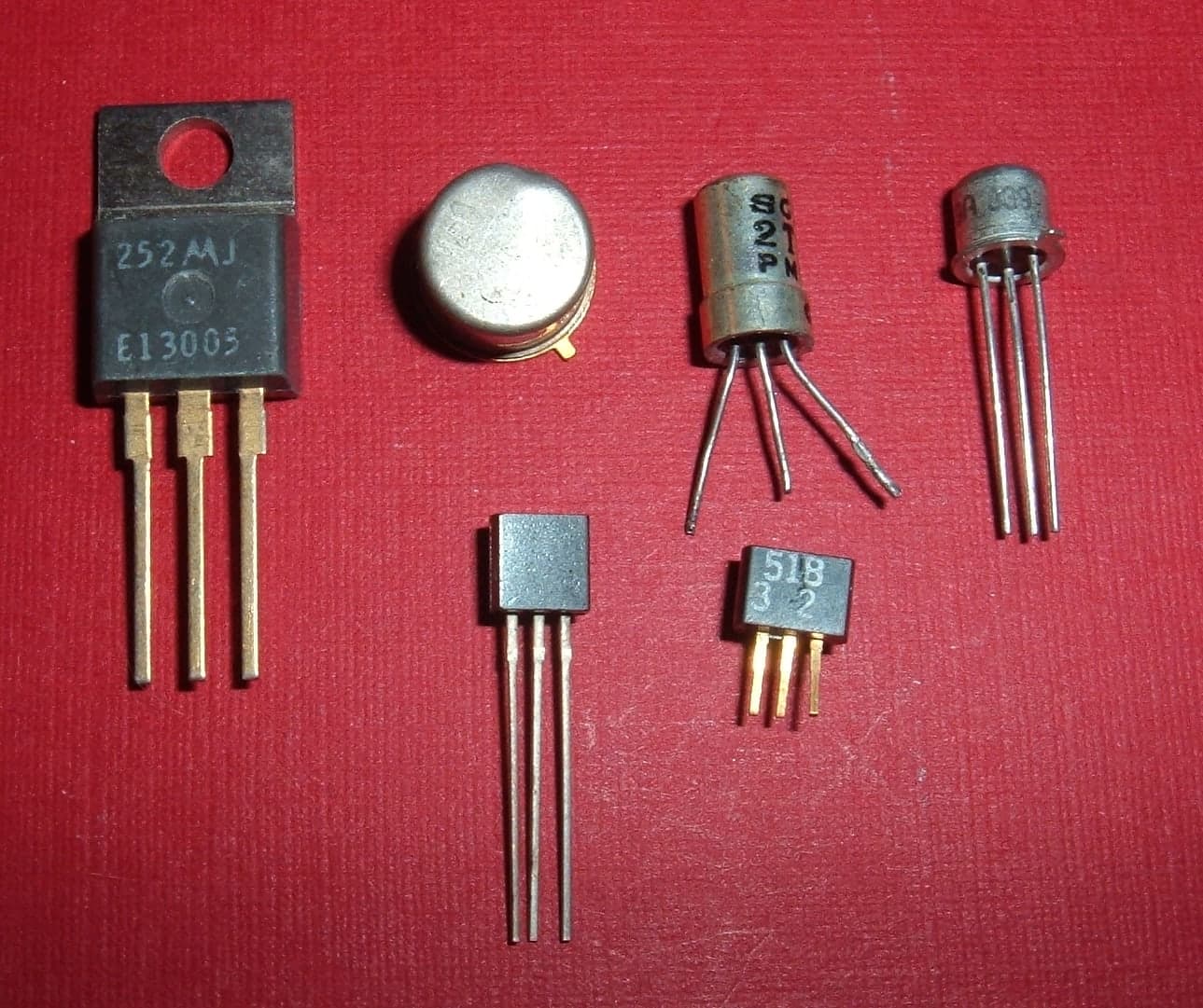 A small electronic component with three wire leads protruding from a black cylindrical body, mounted on a display stand.