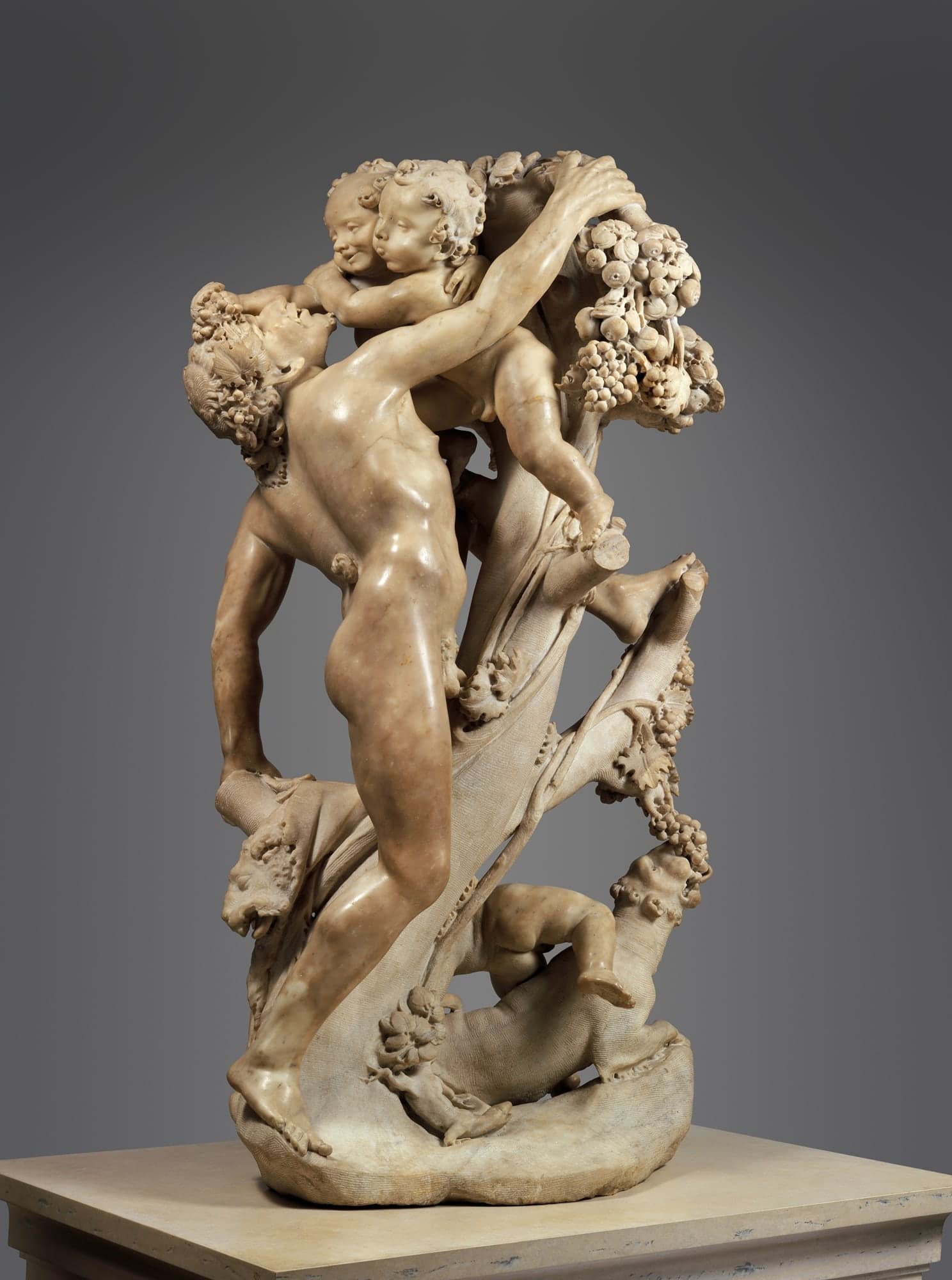A marble sculpture group showing a faun pressed by small children in a tight, twisting cluster of limbs, carved as a single freestanding mass roughly torso height.