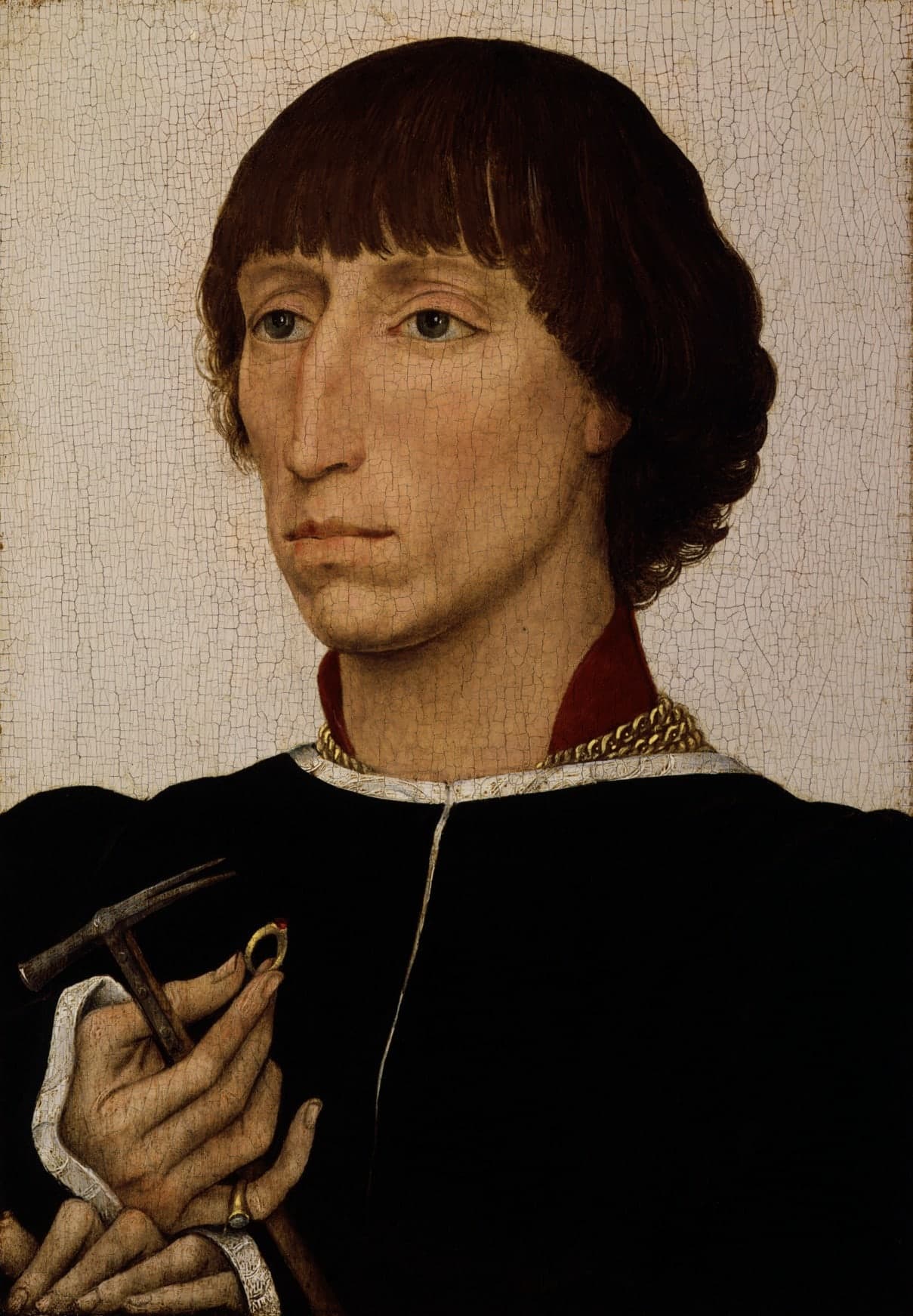 Small half-length portrait of a man in three-quarters view against a plain pale ground, holding a hammer and ring, with long carefully modelled fingers near the lower edge.